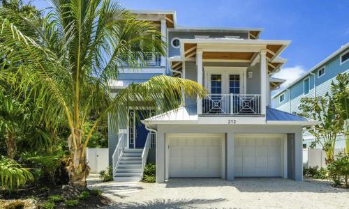uma casa na praia com uma palmeira em Anna Maria Beach House, 5 beds 6,5 baths, roof-top deck and pet-friendly! em Anna Maria