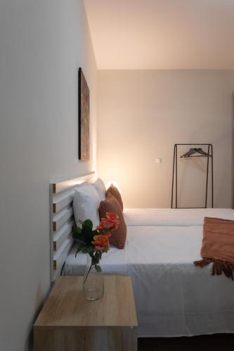 a bedroom with a bed with a vase of flowers on a table at O Sobrado Mariazinha & Inácio Lima in Praia