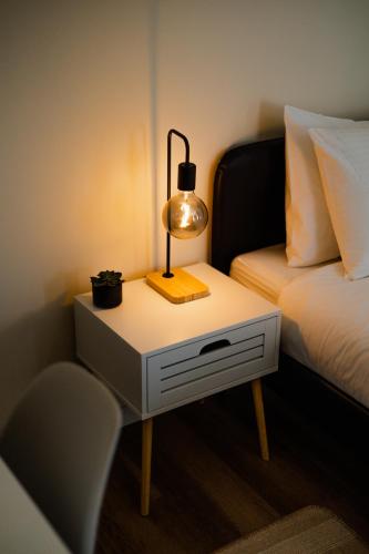 a lamp on a night stand next to a bed at Green Coast Surf House in Espinho