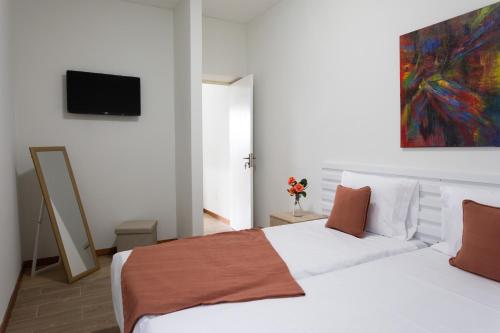 a bedroom with two white beds and a painting on the wall at O Sobrado Mariazinha & Inácio Lima in Praia