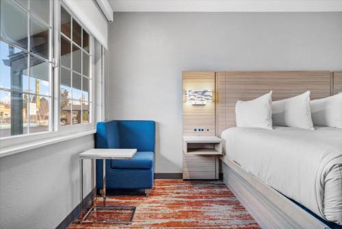 a hotel room with a bed and a blue chair at Cielo House Inn - Paso Robles in Paso Robles