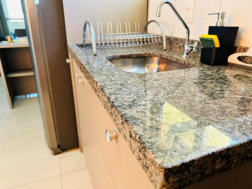 a kitchen with a sink in a granite counter top at Apartamento Cuiabá - Luxxor Flat in Cuiabá