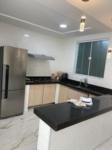 a kitchen with a refrigerator and a black counter top at Mansão do Imperador in Duque de Caxias