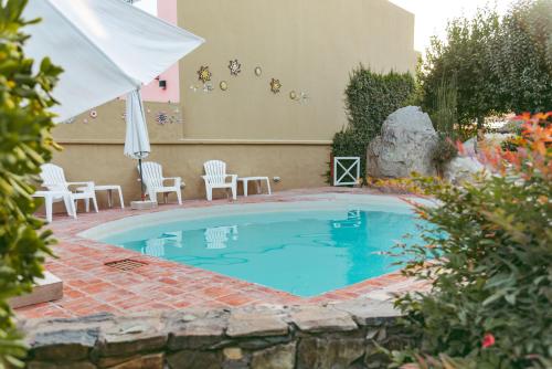 a swimming pool with chairs and an umbrella at Curahue Apart Hotel in Tandil