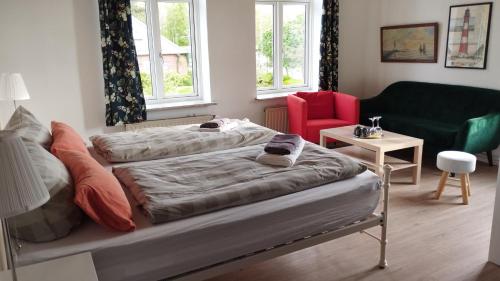 a bedroom with two beds and a green couch at Hoffmanns Nordfriesisches Haus in Tönning