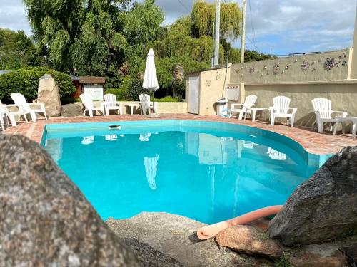 a swimming pool with chairs and a table and chairs at Curahue Apart Hotel in Tandil