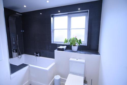 a bathroom with a white tub and a window at Chaucer House Holiday Home in Kent