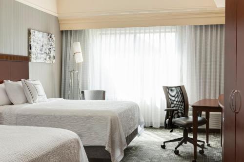 a hotel room with two beds and a desk and a window at Courtyard by Marriott Columbia in Columbia