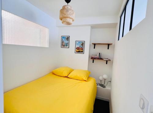 un lit avec des draps jaunes dans une chambre blanche dans l'établissement 2 pièces, 8mn à pied de la croisette/plage, à Cannes