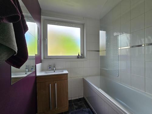 ロンドンにあるModern Central Family-Home for 6のバスルーム(バスタブ、シンク付)、窓が備わります。