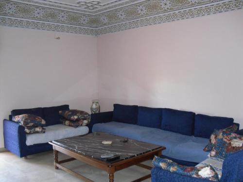een woonkamer met een blauwe bank en een tafel bij VILLA PLAISANCE in Meknès