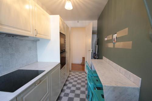 - une cuisine avec des placards blancs et un sol en damier dans l'établissement Spacieux 2 Pièces Montmartre, à Paris