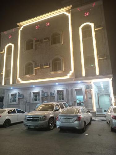 un bâtiment avec des voitures garées devant lui dans l'établissement شقق المجد للشقق المخدومة, à Khobar