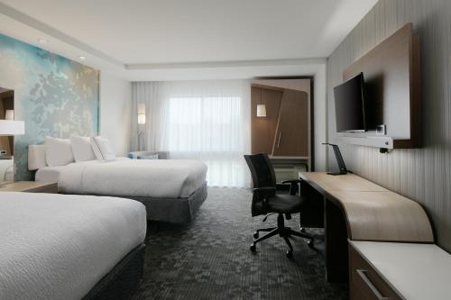 a hotel room with two beds and a desk at Courtyard by Marriott Omaha Bellevue at Beardmore Event Center in Bellevue
