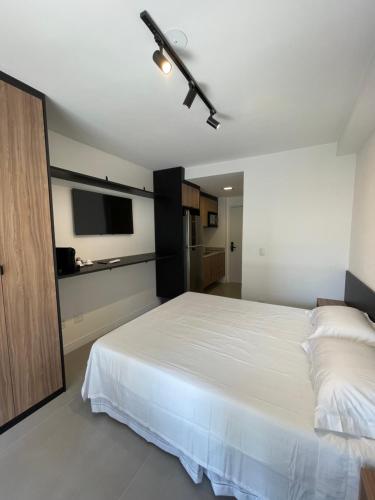 a bedroom with a white bed and a flat screen tv at Studio Luxo Expo SP Itaú in Sao Paulo