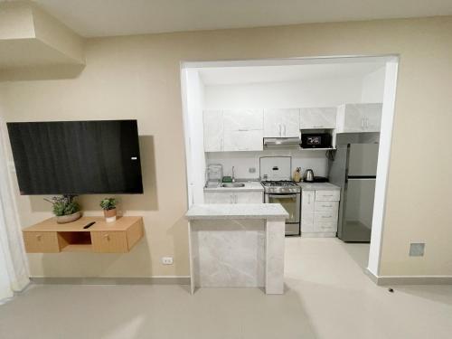 cocina con armarios blancos y TV de pantalla plana en Exclusivo departamento en condominio con Piscina, en Piura
