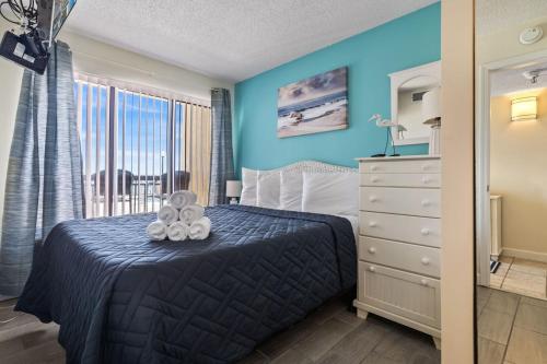een slaapkamer met een bed met blauwe muren en een raam bij Beautiful 2 Bedroom Apartment in Cherry Grove with Stunning Views Buena Vista 402 in Myrtle Beach
