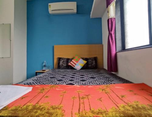 1 dormitorio con 1 cama grande y pared azul en Ambient Homestay by NESTEASY, en Nashik