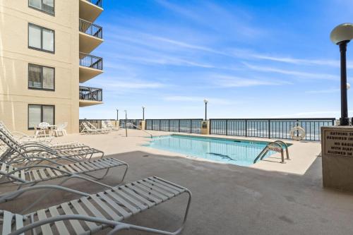 a swimming pool with chairs and a building at Beautiful 2 Bedroom Apartment in Cherry Grove with Stunning Views Buena Vista 402 in Myrtle Beach
