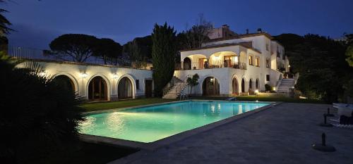 una casa grande con piscina frente a ella en Villa Maricel, en Sant Feliu de Guíxols