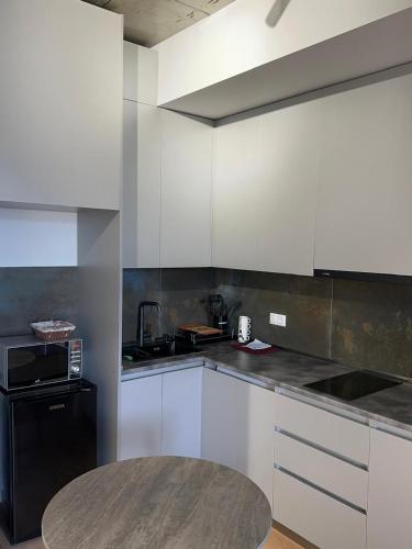 eine Küche mit weißen Schränken und einem schwarzen Kühlschrank in der Unterkunft Annia Apartament in Tbilisi City