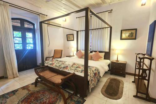 a bedroom with a canopy bed and a chair at Stelliam's Luxury Heritage Suite in Campal, Goa in Panaji