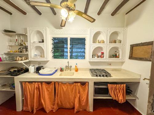 Kaleb's Beachfront Villa في ماليندي: مطبخ مع دواليب بيضاء ومروحة سقف