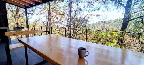 una tazza di caffè seduta su un tavolo di legno sul balcone di Cabaña La Finca Mazamitla a Mazamitla