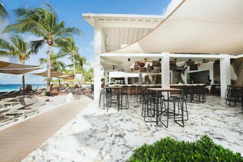 an outdoor bar with chairs and tables on the beach at Papagayo Beach Hotel in Willemstad