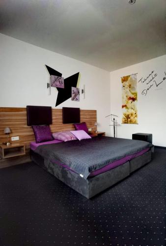 a bedroom with a large bed with purple pillows at Lion Blue Point Hotel in Tulln