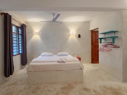 ein weißes Schlafzimmer mit einem Bett und einem Fenster in der Unterkunft Kaleb's Beachfront Studios in Malindi