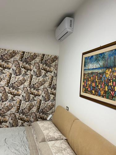 un canapé dans une pièce avec un tableau mural dans l'établissement Rifugio collina del Sacro Cuore, à Ascoli Piceno