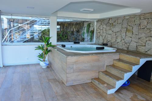 uma banheira de hidromassagem num quarto com uma parede de pedra em Casa Oásis do Moreno 6 em Vila Velha
