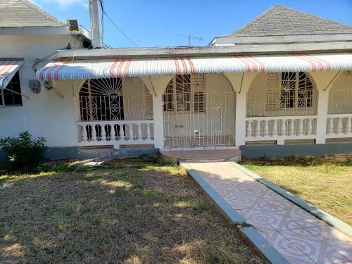 a white house with a porch with an awning at Cozy Apartment Greenwood in Montego Bay