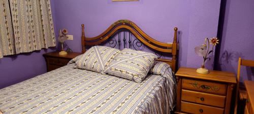 ein lila Schlafzimmer mit einem Bett mit einem Kopfteil aus Holz in der Unterkunft Apartamento Ideal para Grandes Familias in Miramar