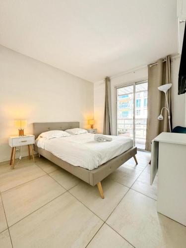 une chambre avec un grand lit et une grande fenêtre dans l'établissement Villa D'Este - Apt 4 prs - clim - 300m plage - piscine-parking en option, à Juan-les-Pins