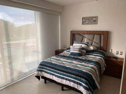 a bedroom with a bed and a large window at Tu espacio ACAPULCO in Acapulco