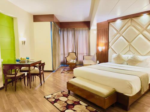 River Grand View Resort and SPA Manali - A River side Property في مانالي: غرفة نوم بسرير ومكتب وطاولة