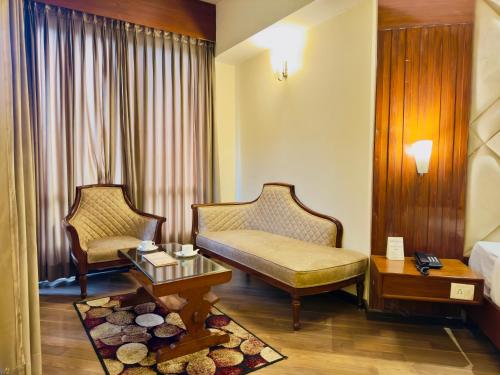 River Grand View Resort and SPA Manali - A River side Property في مانالي: غرفه فندقيه بسرير واريكه وطاولة