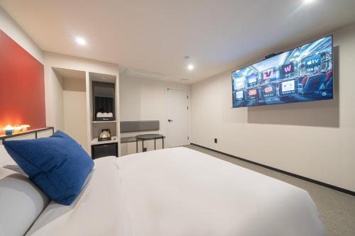 a bedroom with a white bed and a tv on the wall at Hotel Lavanda in Incheon