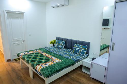 a bedroom with a bed with a green comforter at Agrah Stay - Kasa Lusso Stay in Faridabad