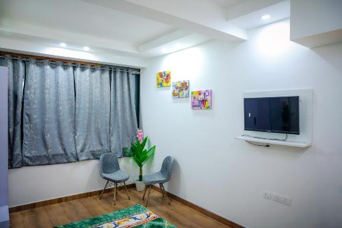 sala de estar con 2 sillas y TV de pantalla plana en Agrah Stay - Kasa Lusso Stay en Faridabad