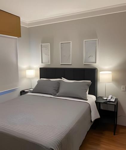 a bedroom with a large white bed with two lamps at Airfamily Congonhas in Sao Paulo
