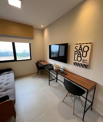 a living room with two desks and a tv at Airfamily Congonhas in Sao Paulo