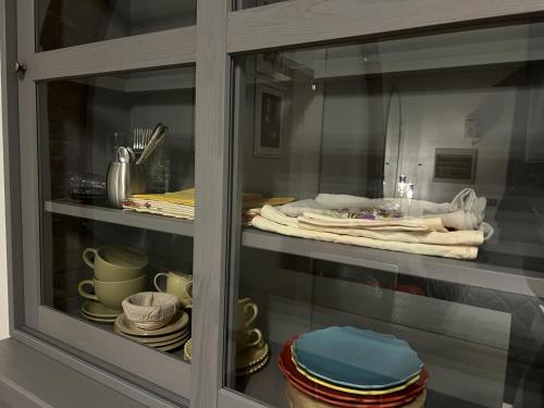 une armoire en verre remplie d'assiettes et de vaisselle dans l'établissement Casa della Noce, à Vinci