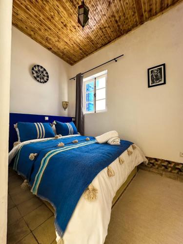 a bedroom with a bed with blue and white sheets at Riyad zen oasis in Essaouira