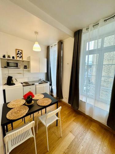 une cuisine avec une table et des chaises et une cuisine avec une fenêtre dans l'établissement Le clair de lune - hyper centre, à Charleville-Mézières