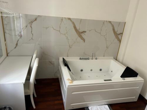 uma banheira branca na casa de banho com paredes em mármore em EXE NAPOLI STADIUM APARTMENT em Nápoles