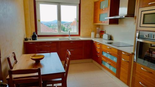eine Küche mit einem Tisch, einem Fenster und einem Waschbecken in der Unterkunft Casa Ría de Vigo in Moaña