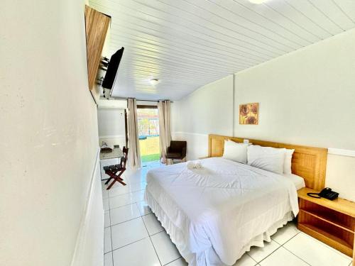 um quarto com uma cama branca num quarto em Hotel Arrastão em São Sebastião